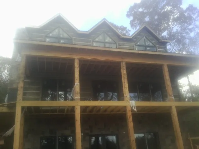 Dormers and porch framing on a large log home under construction — Roof Coating work by our crew in Nobleton