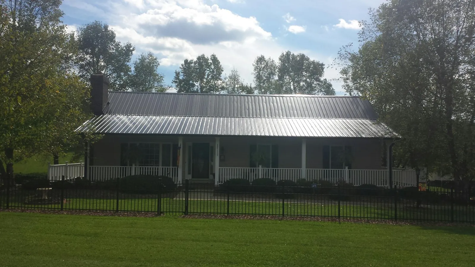 Gray metal roof on a brick ranch with a full width front porch — Gutter Guard Installation work by our crew in Nobleton